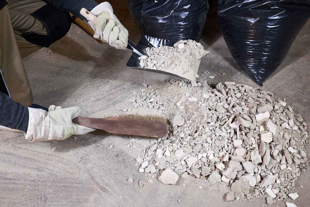 person sweeping construction debris into a dustpan