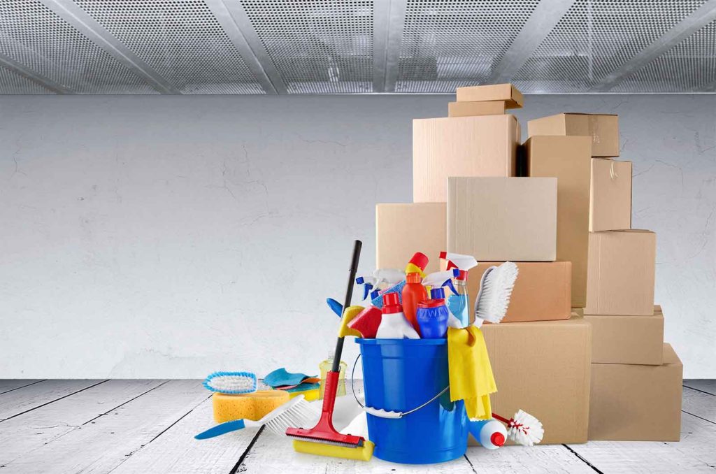 stack of moving boxes with a collection of cleaning supplies beside them